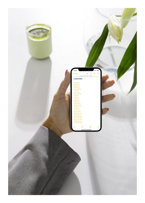 Photo of a hand holding a phone displaying a list of Hashtags to use for an Instagram post.